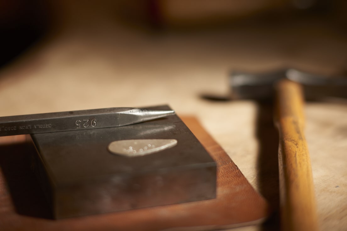 Gros plan sur une médaille en argent et des outils de bijoutier. Bijouterie-joaillerie sur-mesure